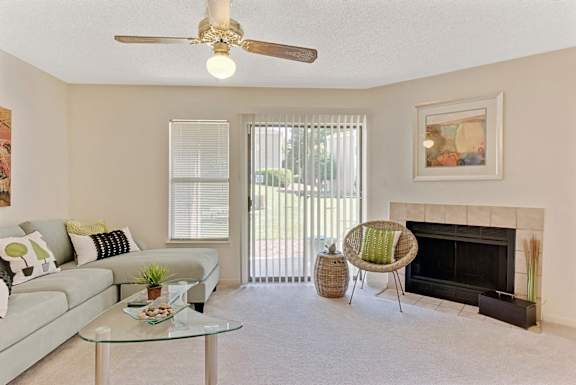 A living room with a fireplace, a couch, a chair, and a table at Fox Hollow Apartment Homes, North Carolina