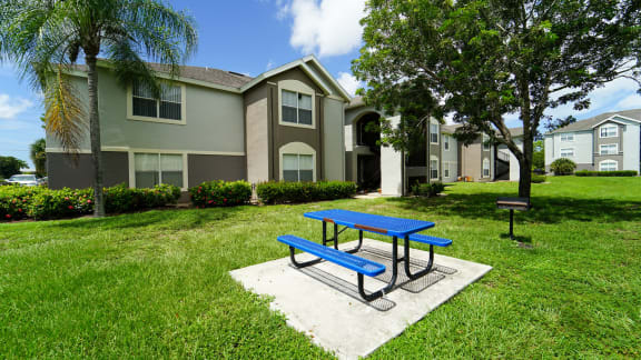 Outdoor picnic area surrounded by native landscaping and apartment building exterior in the background