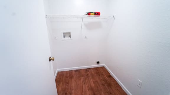 Full-sized washer and dryer room with hardwood style flooring