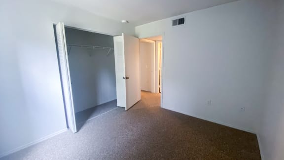 Carpeted Bedroom with folding closet doors, bedroom door leads to hall and bathroom