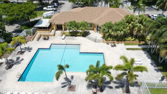 Aerial view of Swimming Pool with Sundeck, Lounge Chairs and Palm Trees at Sunset