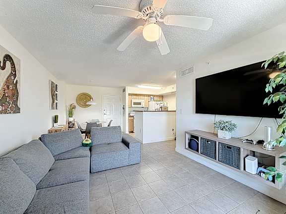 A living room with a grey sofa and a black TV on the wall.