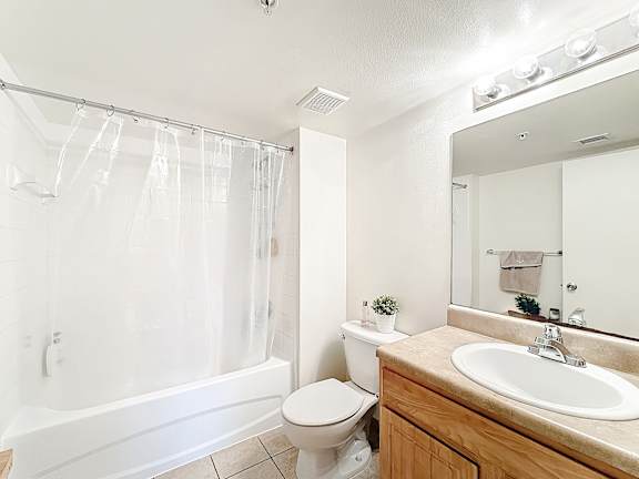 A white bathroom with a toilet, sink, and shower.