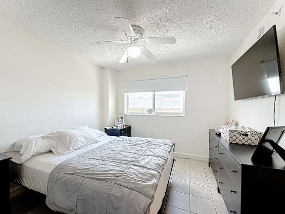A bedroom with a bed, dresser, and ceiling fan.