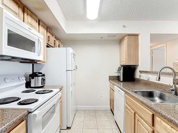 A kitchen with white appliances and wooden cabinets.