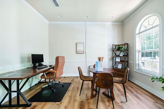 A room with a desk, chairs, and a bookshelf.