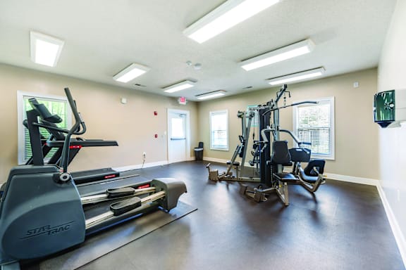 A gym with a treadmill, elliptical trainer and a weight machine.