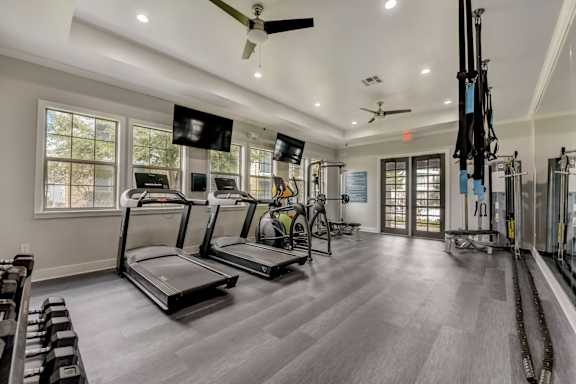 A spacious gym with treadmills, elliptical machines, and a television.