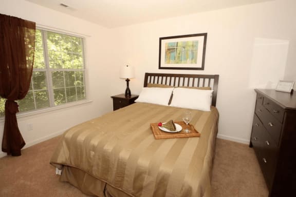 Bedroom with carpet flooring, dresser, night stand, desk lamp, and wall art