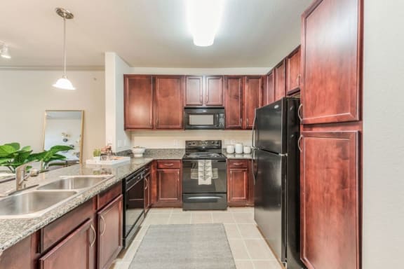 a kitchen with dark wood cabinets and black appliances