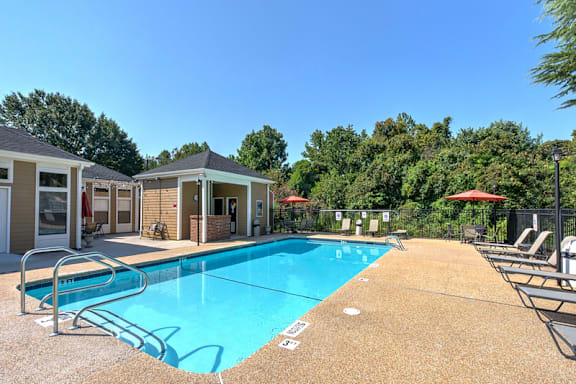 A pool surrounded by trees and chairs at Fox Hollow Apartment Homes, High Point, 27265