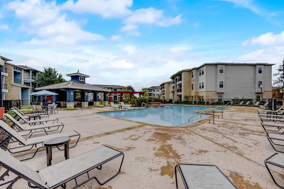 A pool area with sun loungers and a small building in the background.