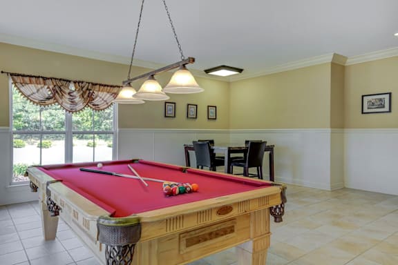 A pool table with a red cloth and a pool cue on it at Ethan Pointe Apartments, Greensboro