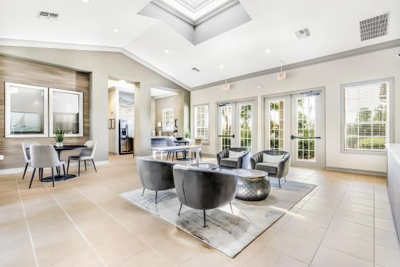 Clubhouse with several conversational seating areas along a wall of windows and glass doors.