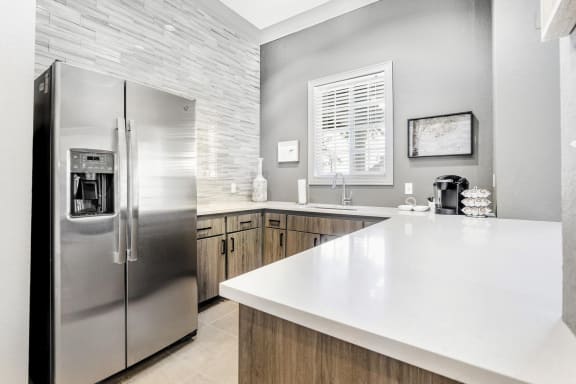 Clubhouse kitchen with white countertops, a sink, and a stainless steel french door refrigerator.