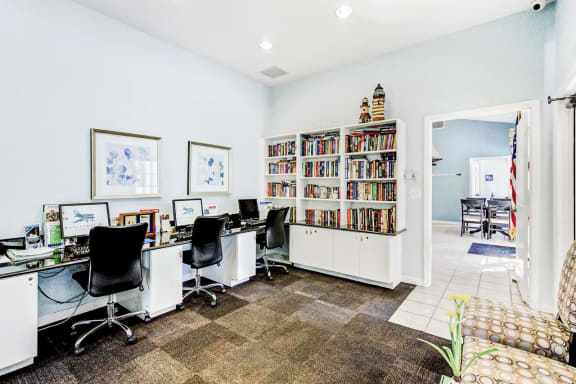 Business Center with Computers on Desk Counters with Office Chairs Next to Fully Stocked Bookshelf
