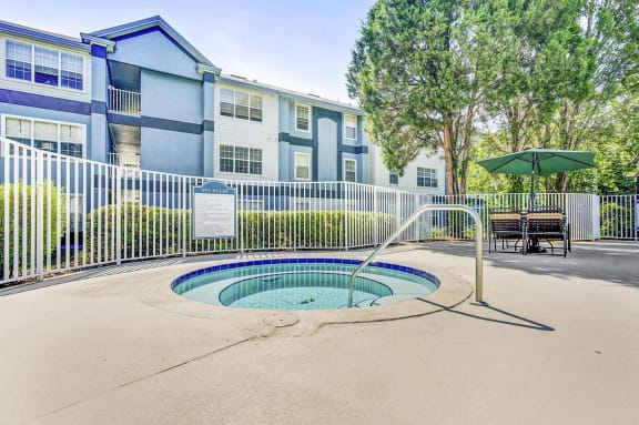 Hot Tub Next to Pool Fence with Building Exterior in the Background