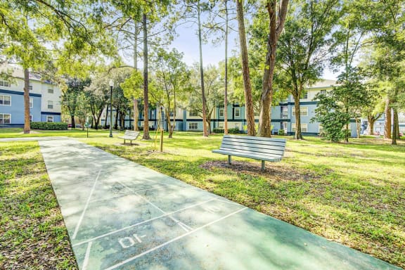 Concrete Shuffleboard Next to Bench in Courtyard Shaded by Trees