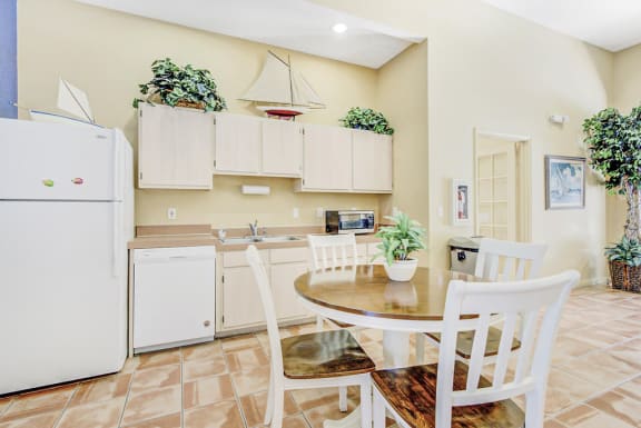 Clubhouse kitchen with round table, white appliances and tan cabinetry