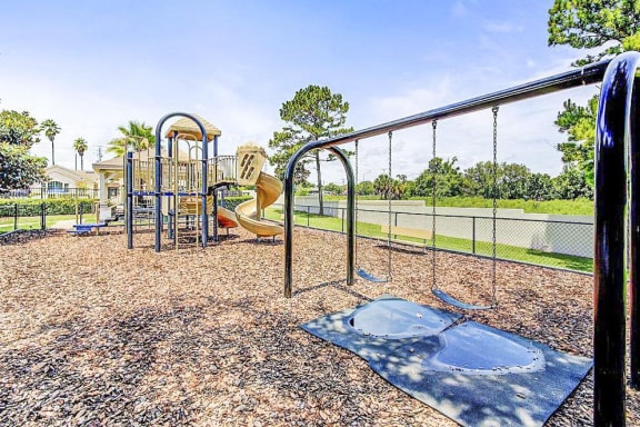 Playground equipment with a slide and a separate swing set with two swings.