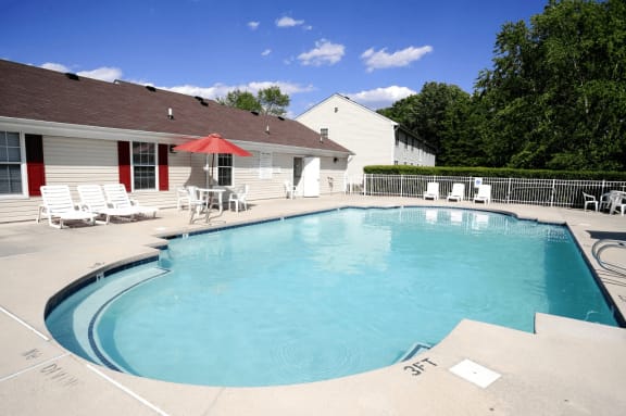 Swimming pool with lounge seating, picnic seating with umbrella shading, native landscaping surrounding the exterior