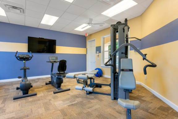 Fitness center equipped with strength training equipment, cardio equipment, mounted tv, and yoga equipment