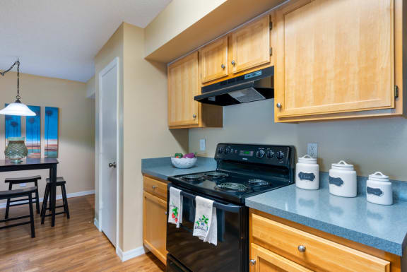 Kitchen with Wood Cabinets, grey Counters and black Appliances