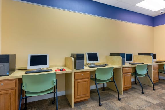 Business center with four desktop computers with flat-screen monitors and four chairs