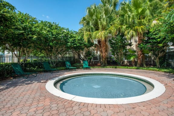 Fenced in Round Wading Pool with Lounge Chairs and Trees in the Background