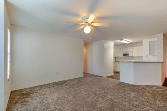 Carpeted Living Room in Open Layout with Breakfast Bar and Kitchen with White Cabinets Visible