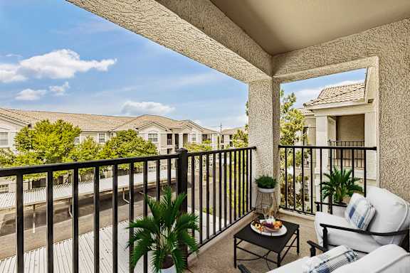 A balcony with a table and chairs overlooking a street.