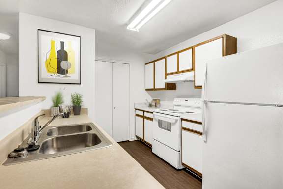 A kitchen with white appliances and a painting of two bottles.