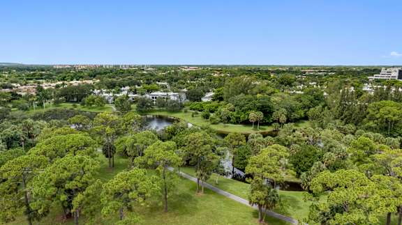 A lush green park with a pond and a building in the distance.