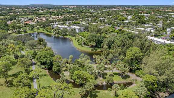 A serene landscape with a lake surrounded by lush greenery and buildings in the distance.