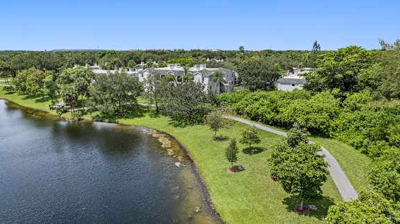 A serene landscape with a lake, trees, and a building in the distance.