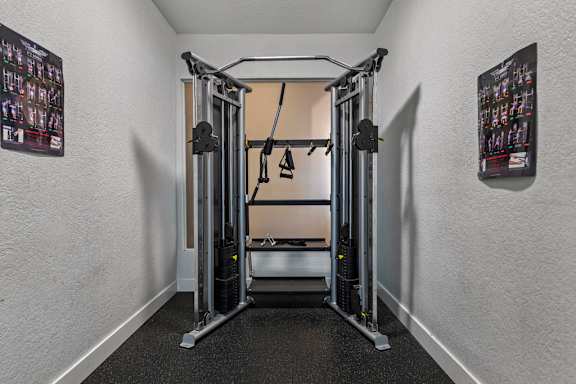 A gym room with a squat rack and a bench.