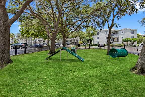 A playground with a green slide and a green barrel.