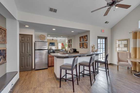 A kitchen with a refrigerator, sink, and bar stools.