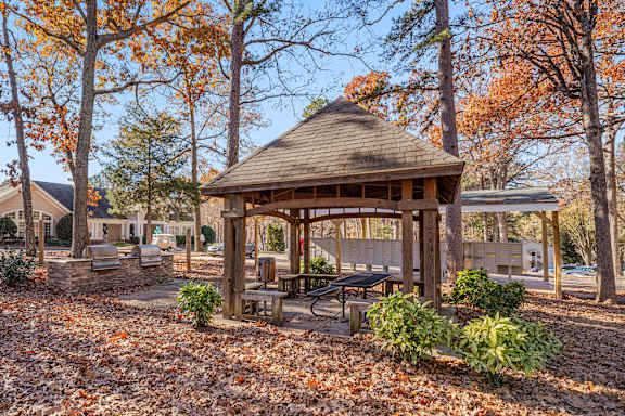 A gazebo surrounded by trees with orange leaves.