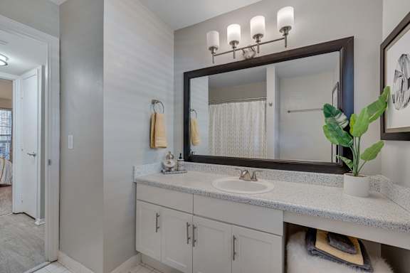 A bathroom with a sink, mirror, and cabinets.