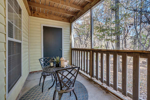 A small table with two chairs is on a porch.