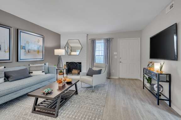 A living room with a grey couch, a coffee table, and a fireplace.