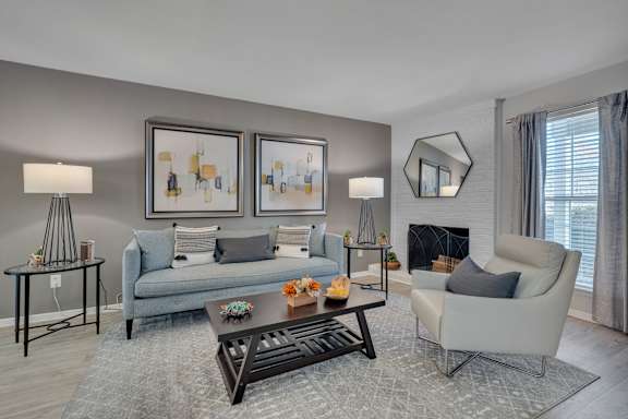 A living room with a grey couch, a white armchair, a coffee table, and two framed pictures on the wall.