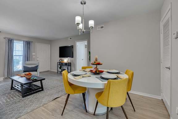 A dining room with a white table and yellow chairs.