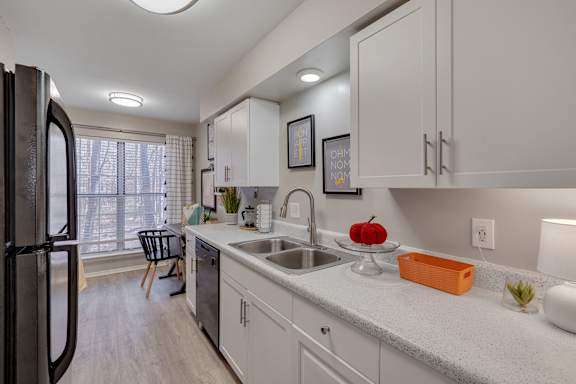 A kitchen with white cabinets and a black refrigerator.