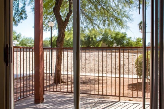 Private Patio with Sliding Glass Doors and Metal Railing Next to Tree