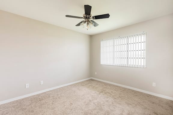 Bedroom with hardwood style flooring with white walls, a window and ceiling fan.