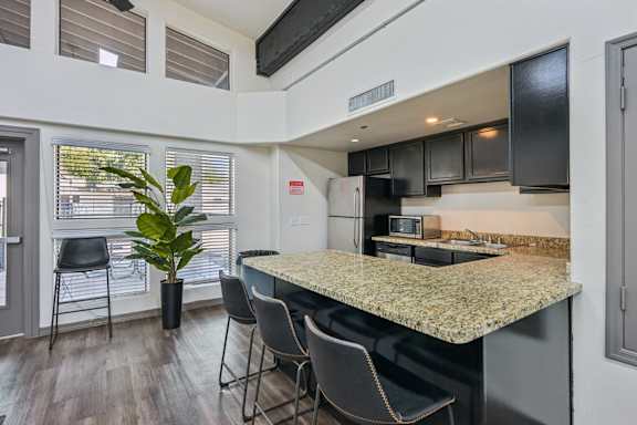 clubhouse kitchen with a granite countertop and black chairs.