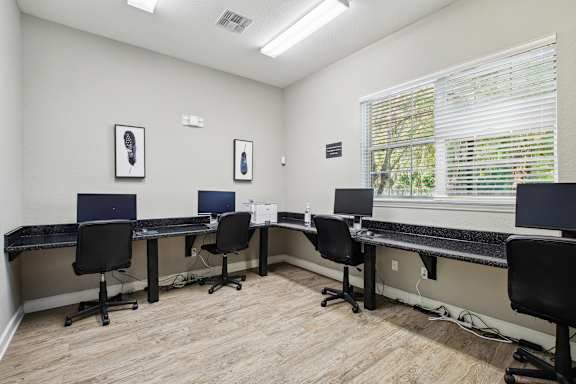 A room with a desk and chairs with a laptop on it.