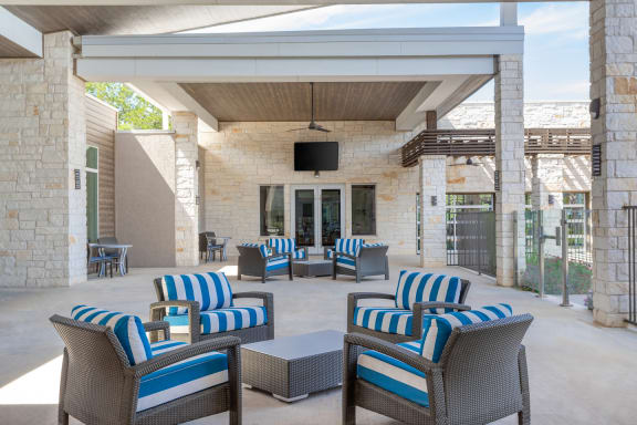 an outdoor patio with blue and white chairs and a television
